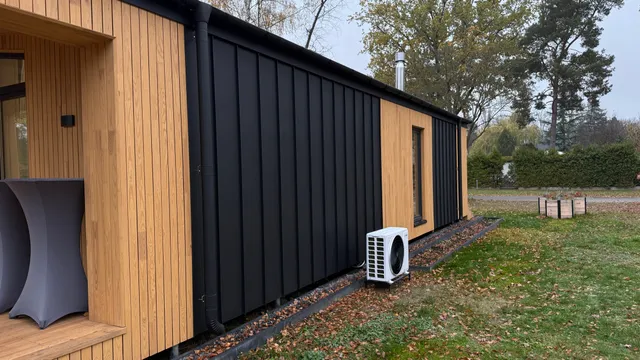Fertiges Modulhaus mit moderner Holz-Metall-Fassade und außenliegender Wärmepumpe für den Energiestandard